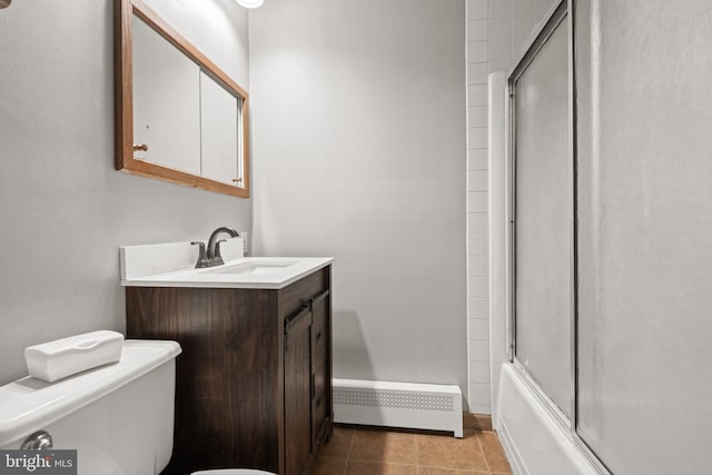 full bathroom featuring toilet, baseboard heating, tile patterned floors, bath / shower combo with glass door, and vanity