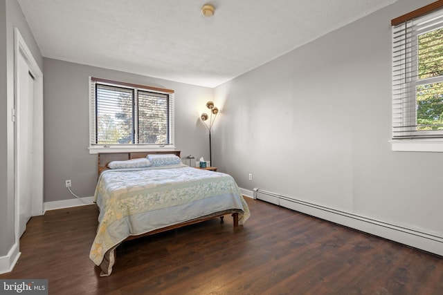 bedroom featuring a textured ceiling, dark hardwood / wood-style floors, multiple windows, and a baseboard radiator