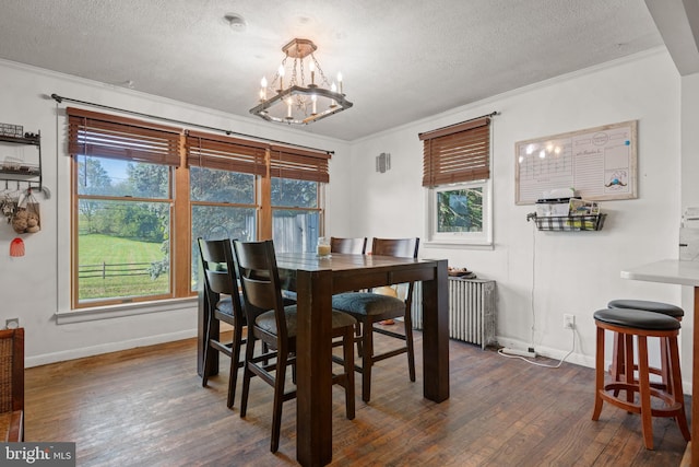 dining room featuring ornamental molding, dark wood-type flooring, an inviting chandelier, and a textured ceiling