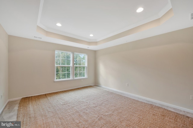 empty room with light carpet, a raised ceiling, and ornamental molding