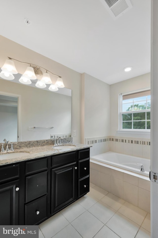 bathroom featuring a relaxing tiled tub, tile patterned floors, and vanity