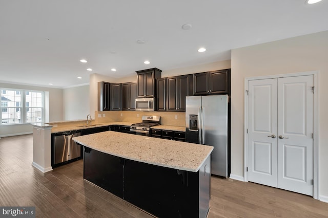 kitchen featuring a kitchen bar, stainless steel appliances, kitchen peninsula, and wood-type flooring