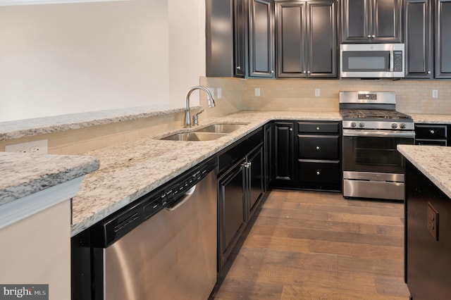 kitchen featuring light stone counters, stainless steel appliances, sink, and dark hardwood / wood-style flooring