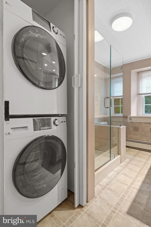 laundry room featuring baseboard heating and stacked washer / dryer