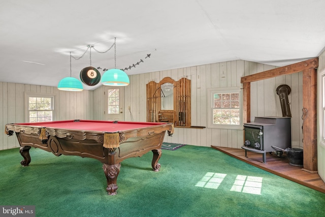 recreation room with a wood stove, a healthy amount of sunlight, hardwood / wood-style flooring, and vaulted ceiling