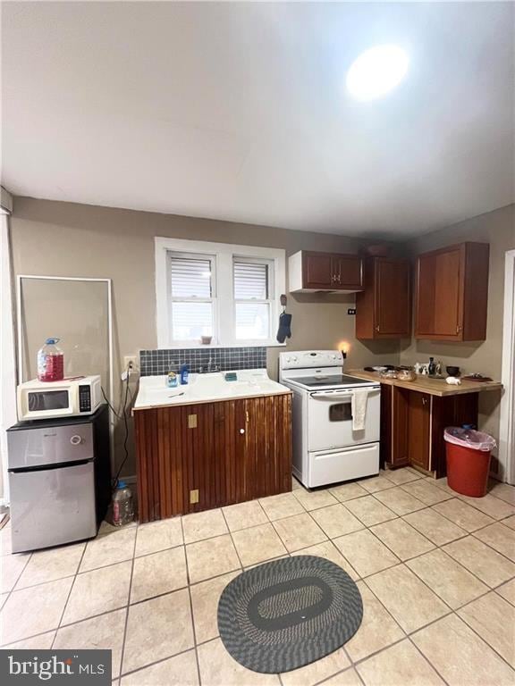 kitchen with white appliances, light tile patterned floors, and backsplash