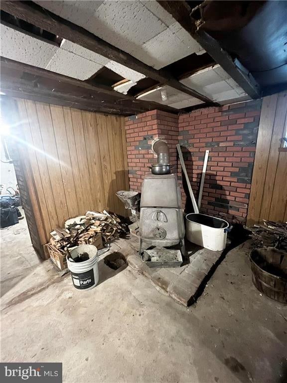 misc room featuring a wood stove, wooden walls, and concrete flooring