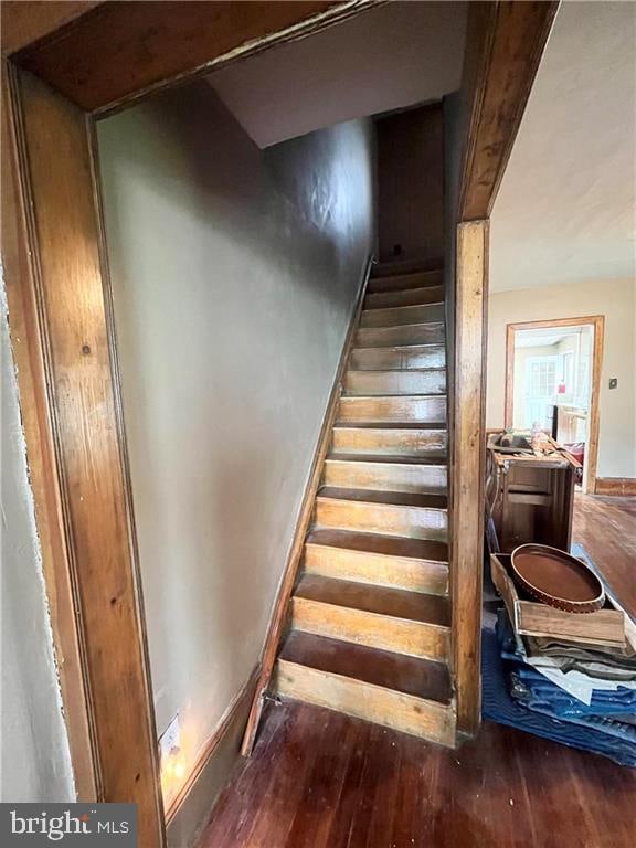 stairway featuring beam ceiling and hardwood / wood-style flooring