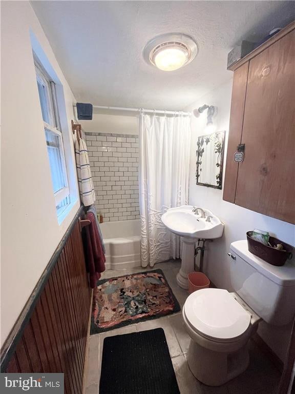 bathroom with a textured ceiling, shower / tub combo, toilet, and tile patterned floors