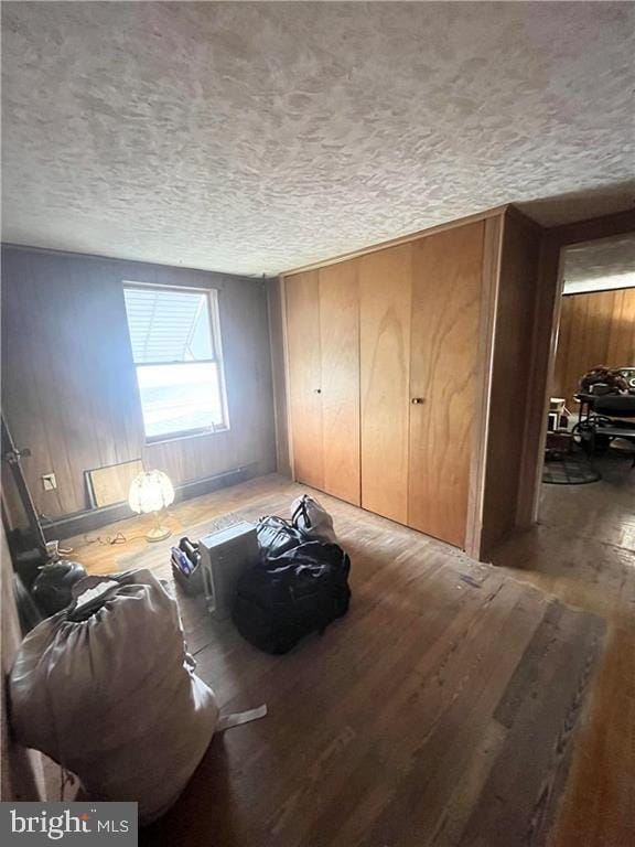 living room featuring a textured ceiling, wood walls, and hardwood / wood-style floors