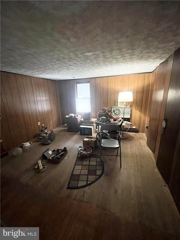 sitting room with a textured ceiling, light wood-type flooring, and wood walls