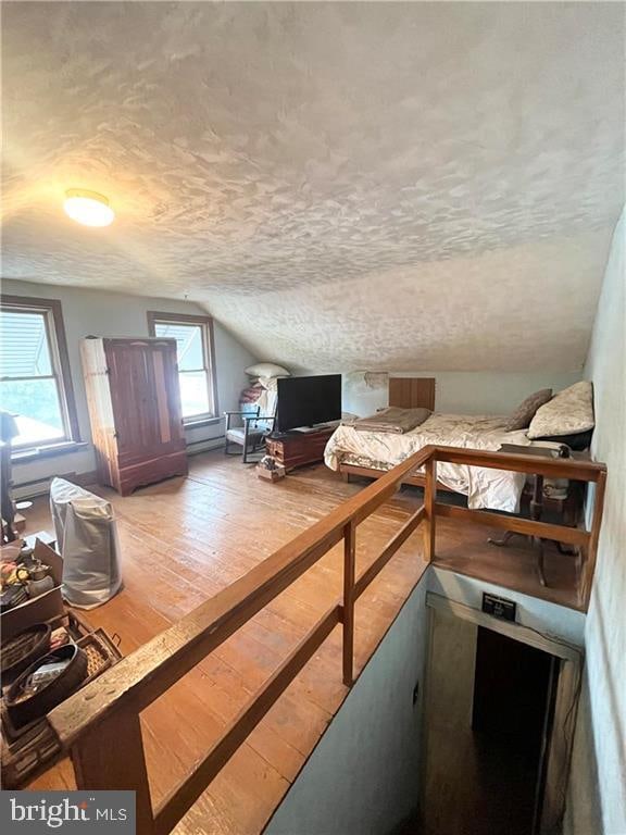 bonus room with vaulted ceiling, a textured ceiling, and hardwood / wood-style floors