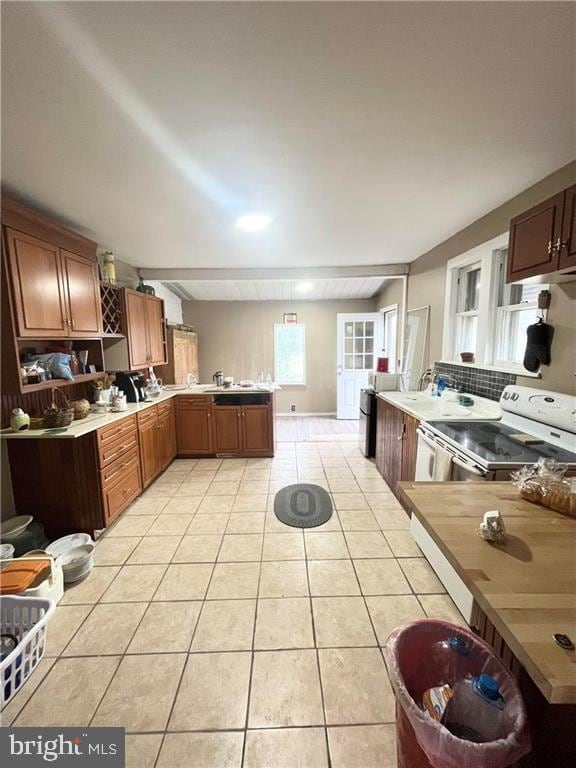 kitchen with kitchen peninsula, range with electric stovetop, light tile patterned floors, and tasteful backsplash