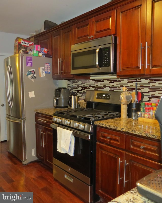 kitchen featuring tasteful backsplash, dark hardwood / wood-style flooring, stainless steel appliances, and light stone counters