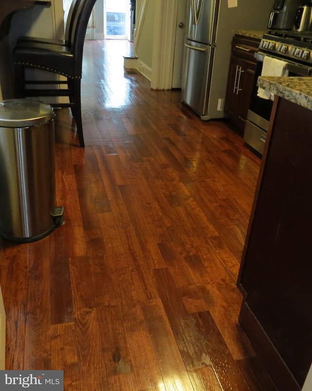 kitchen featuring appliances with stainless steel finishes, dark wood-type flooring, and light stone counters