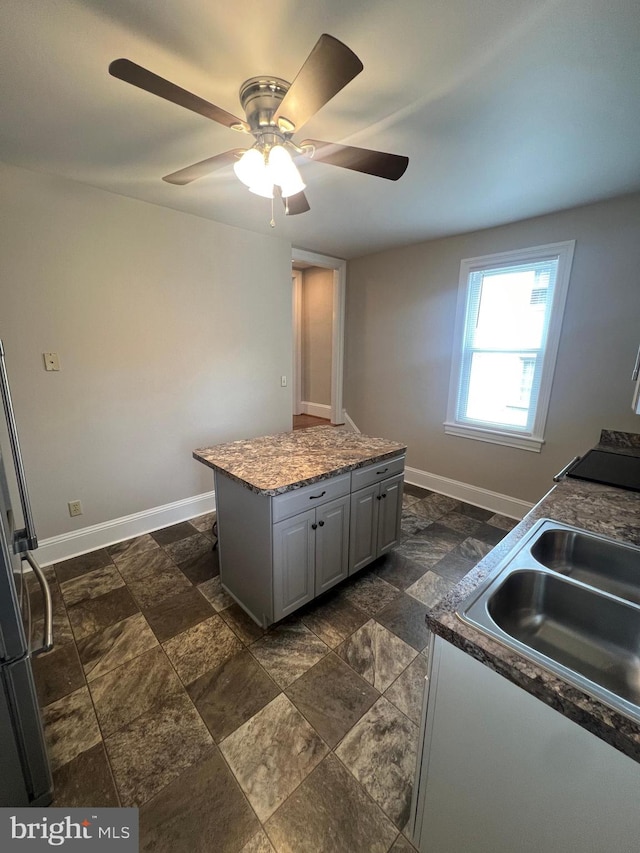 kitchen with ceiling fan, gray cabinets, sink, and a kitchen island