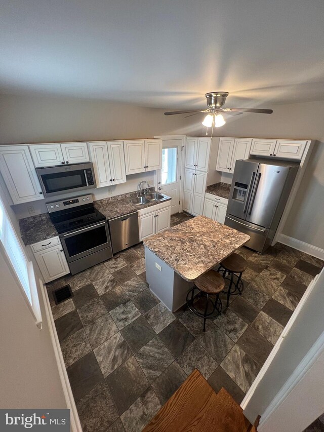 kitchen featuring sink, lofted ceiling, white cabinetry, stainless steel appliances, and ceiling fan