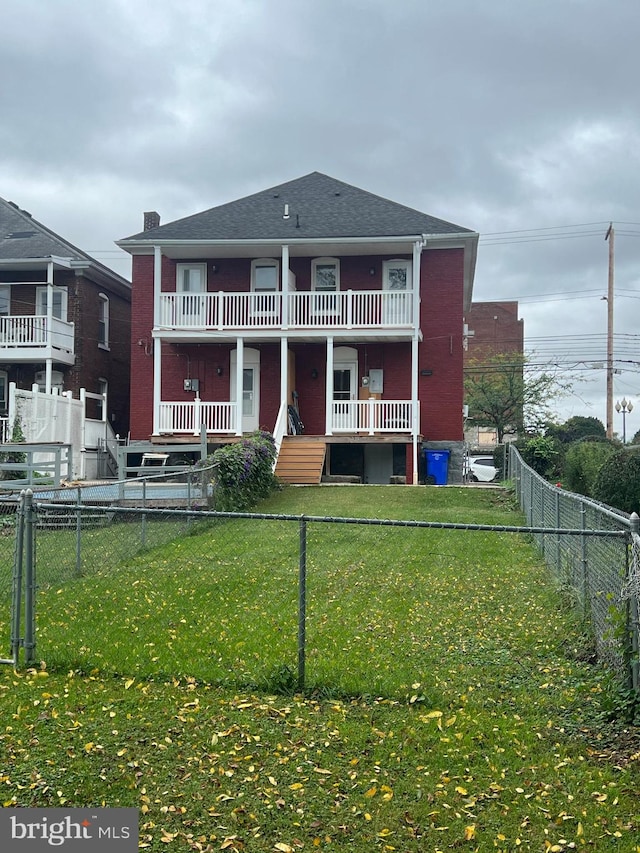 back of house with a balcony and a lawn