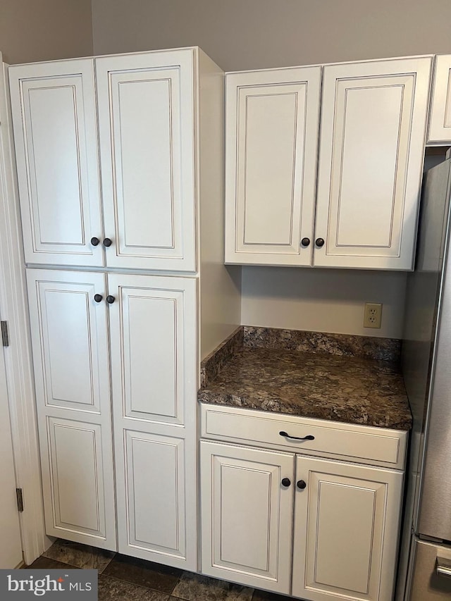 kitchen featuring stainless steel fridge and white cabinetry