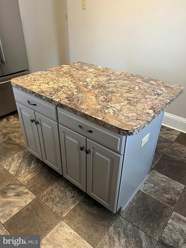 interior details with gray cabinetry, stainless steel refrigerator, and a center island