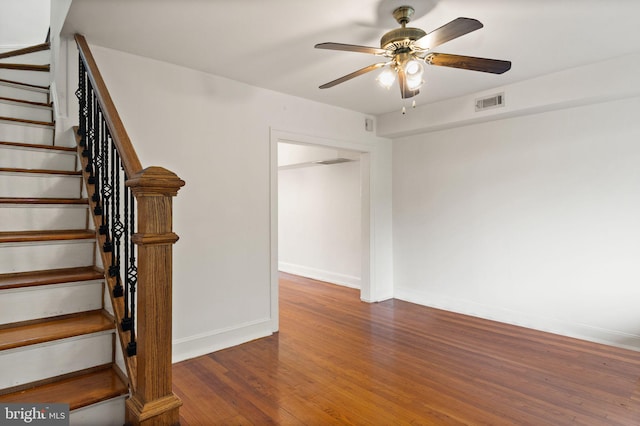 stairway with wood-type flooring and ceiling fan