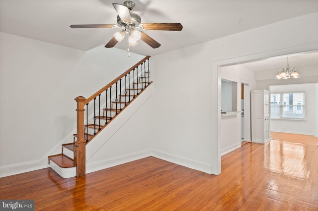 stairway featuring ceiling fan with notable chandelier and wood-type flooring