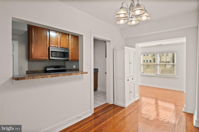 kitchen with wood-type flooring, decorative light fixtures, appliances with stainless steel finishes, and a chandelier