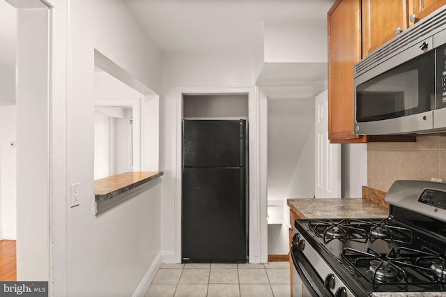 kitchen featuring backsplash, light tile patterned floors, and stainless steel appliances