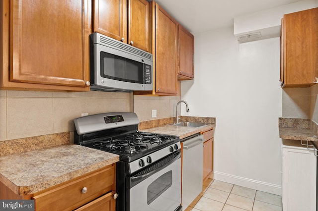 kitchen with light tile patterned floors, stainless steel appliances, sink, and decorative backsplash