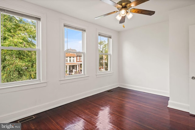 empty room with ceiling fan and dark hardwood / wood-style flooring