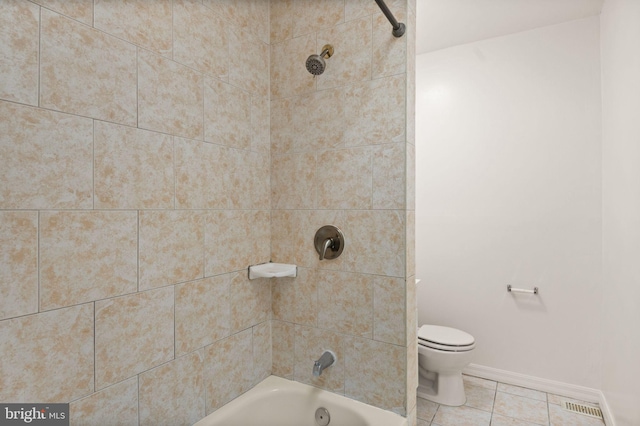 bathroom featuring tiled shower / bath combo, toilet, and tile patterned floors