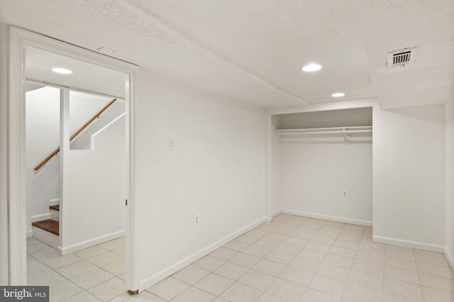 unfurnished bedroom featuring a textured ceiling, a closet, and light tile patterned flooring