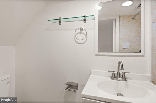 bathroom with tiled shower, vanity, and toilet