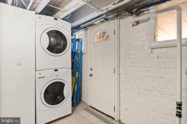 laundry area featuring light tile patterned flooring and stacked washing maching and dryer