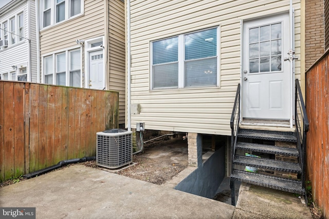 view of exterior entry with a patio area and central air condition unit