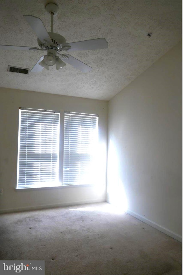 spare room with a textured ceiling, ceiling fan, and light colored carpet