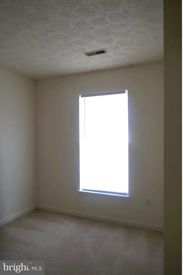 carpeted empty room featuring a textured ceiling