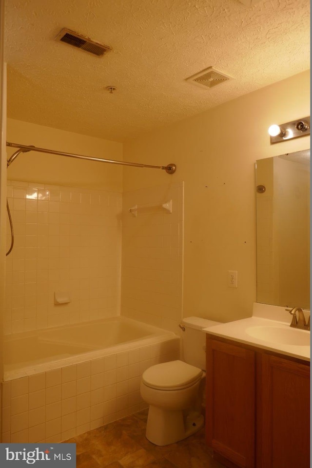 full bathroom with a textured ceiling, tiled shower / bath combo, vanity, and toilet