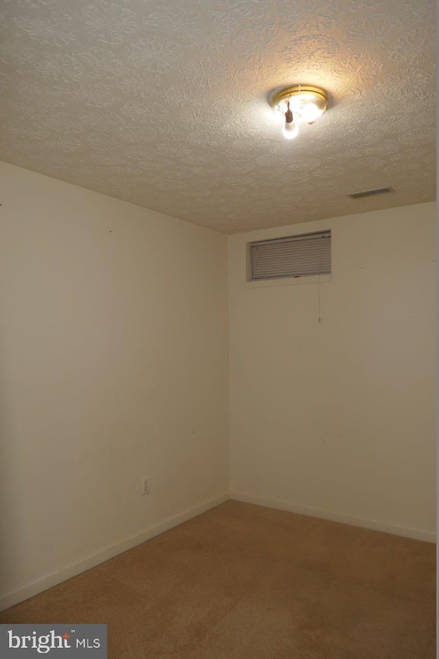 carpeted empty room featuring a textured ceiling