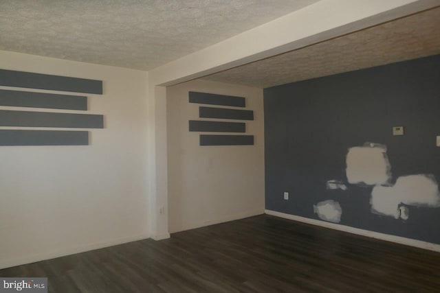 spare room with a textured ceiling and dark hardwood / wood-style floors