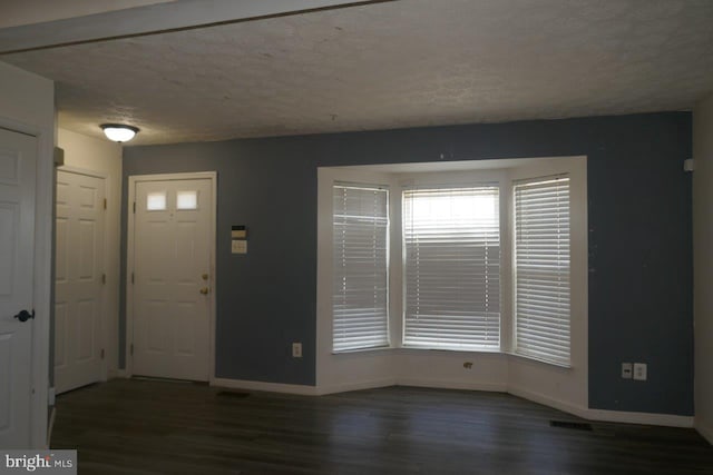 foyer entrance featuring a textured ceiling and dark hardwood / wood-style floors