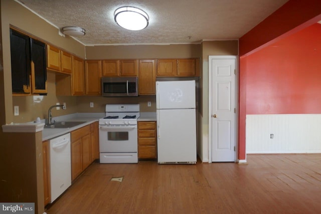 kitchen with a textured ceiling, light wood-type flooring, sink, and white appliances