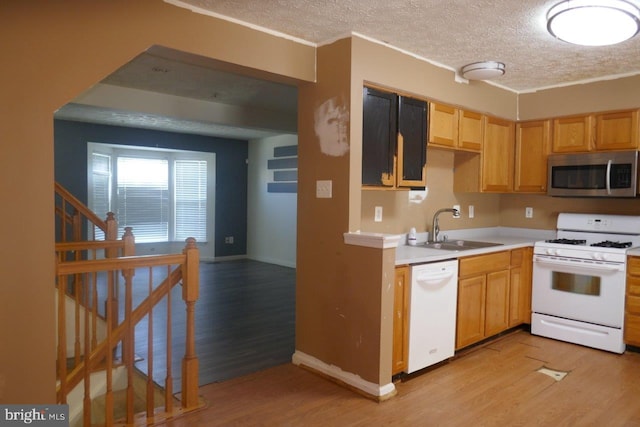 kitchen with light hardwood / wood-style floors, a textured ceiling, white appliances, and sink