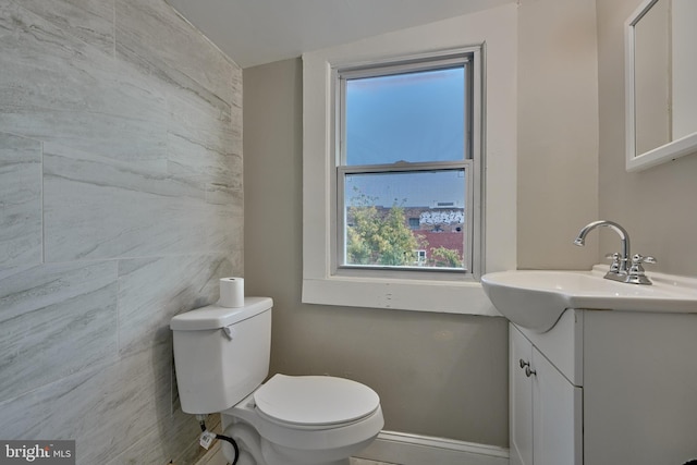 bathroom with tile walls, vanity, and toilet