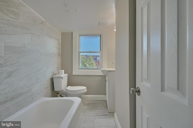 bathroom featuring vanity, toilet, a bath, tile walls, and vaulted ceiling