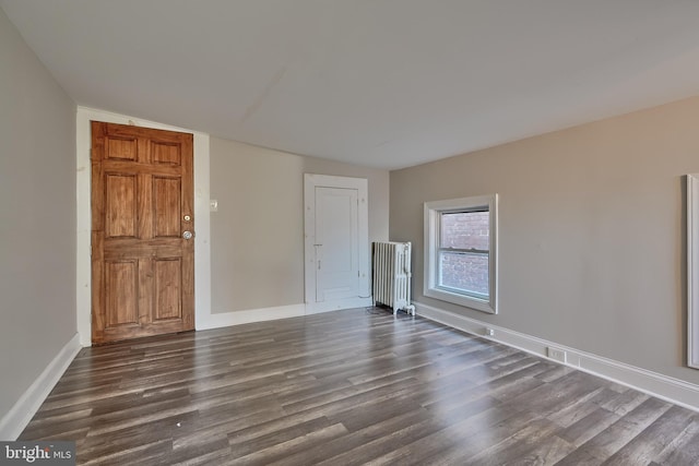 empty room featuring radiator, dark hardwood / wood-style floors, and vaulted ceiling