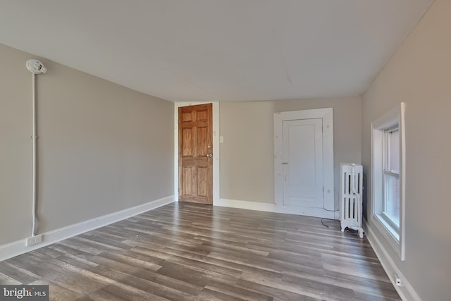 unfurnished room featuring radiator and hardwood / wood-style floors