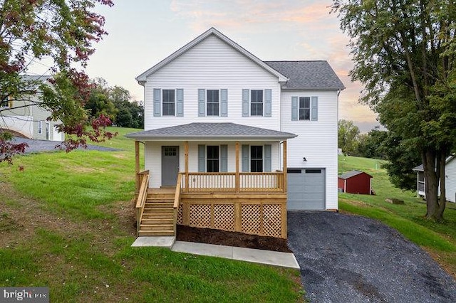 view of front of home with a lawn, a porch, and a garage