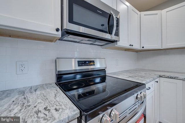 kitchen with backsplash, white cabinetry, light stone countertops, and stainless steel appliances