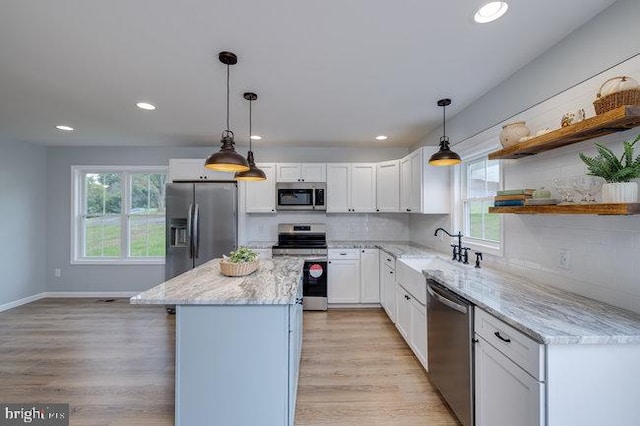 kitchen featuring decorative light fixtures, stainless steel appliances, and white cabinets